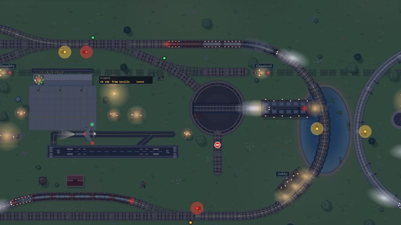 The engine yard and airport at night, lamp pools and train headlights glowing on the dark table
